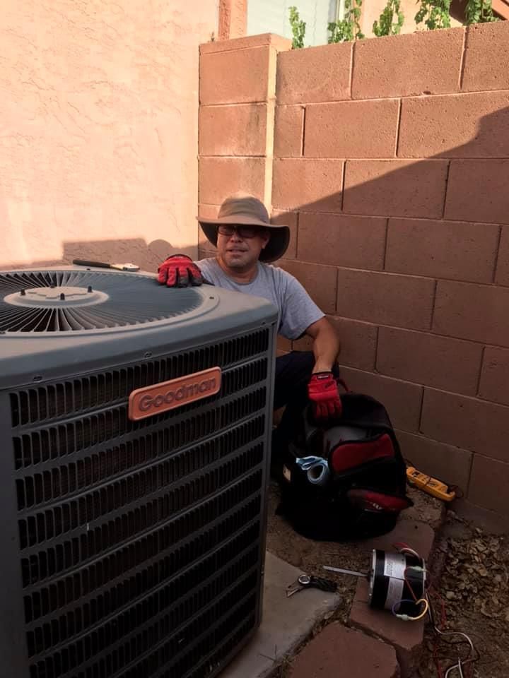 a man wearing a hat and gloves is sitting next to an air conditioner .