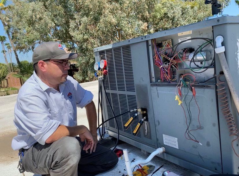 a man is kneeling down next to a large air conditioner .