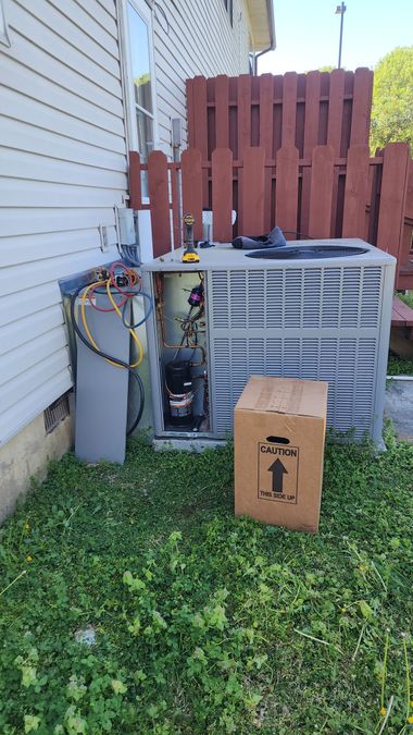 Technician using a digital manifold gauge on an outdoor air conditioner unit.