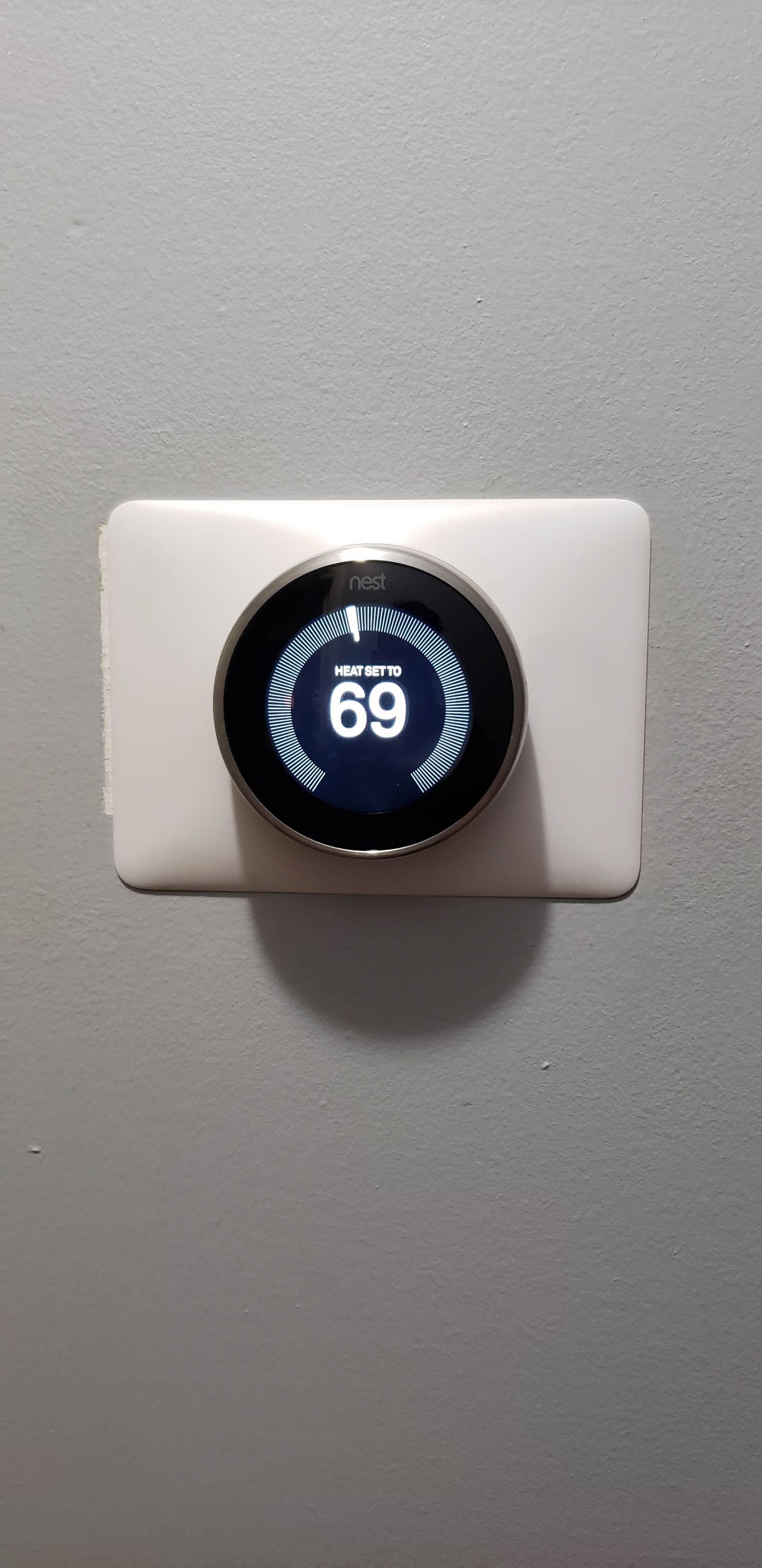 Hand pressing a doorbell on a white wall near a bright living room