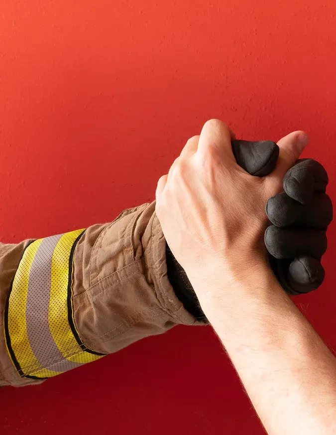 A firefighter is shaking hands with another firefighter