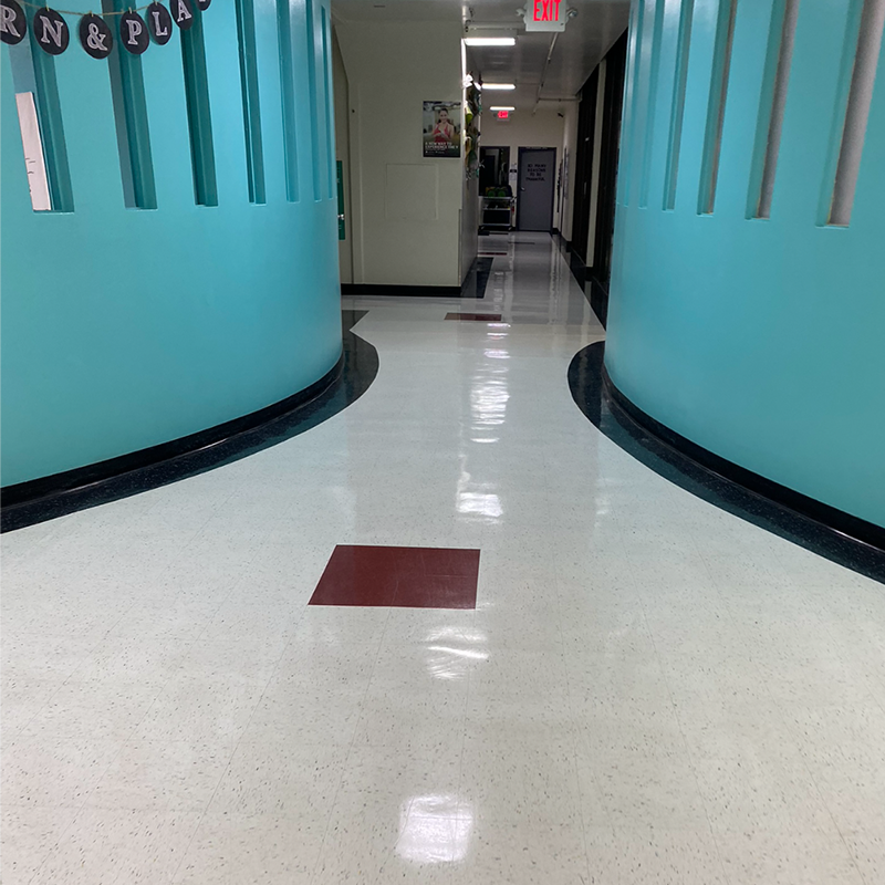 Empty school hallway with turquoise curved walls and shiny white floor tiles