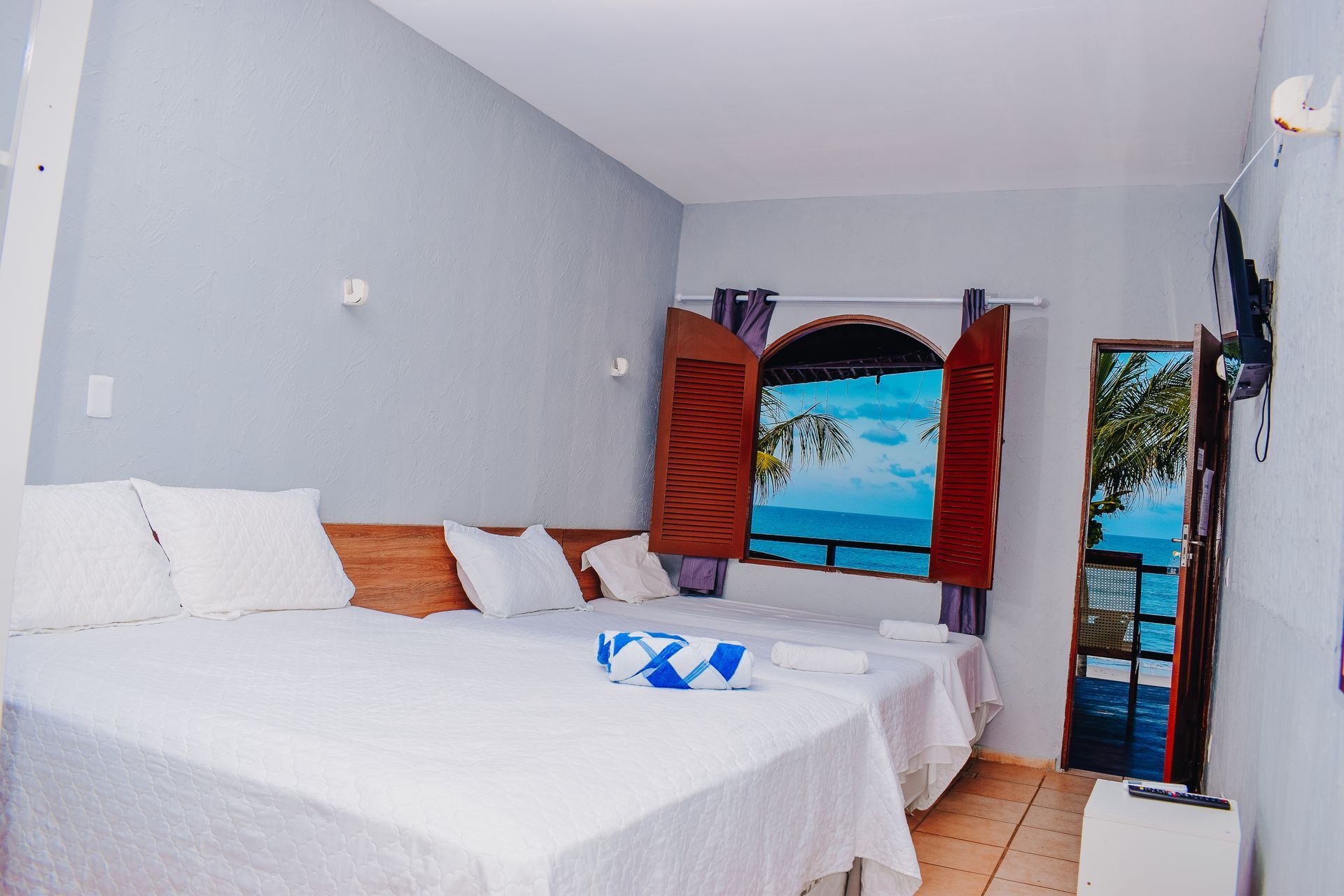 A hotel room with two beds and a window overlooking the ocean.