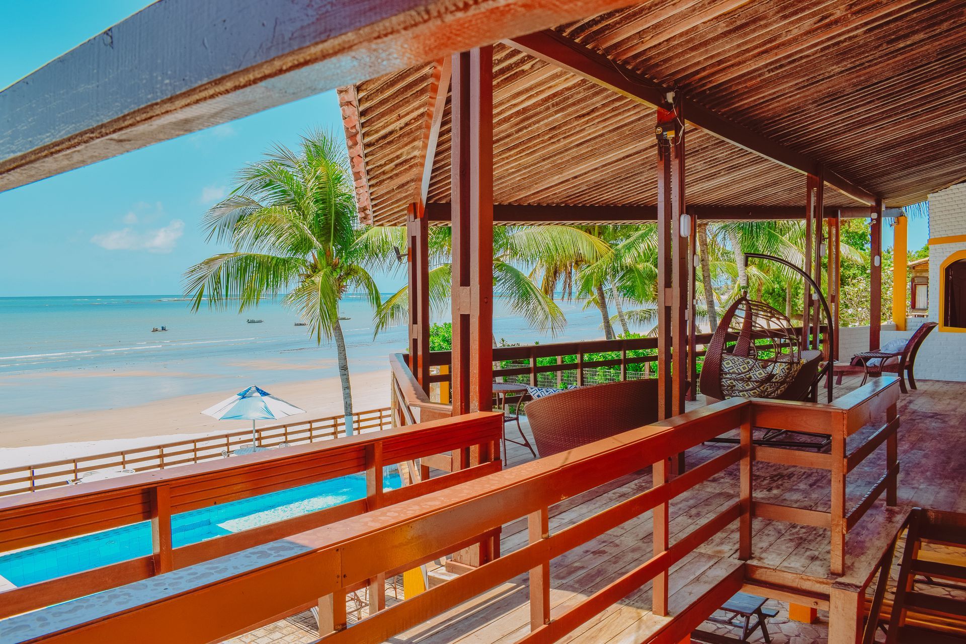 A wooden deck with a view of the ocean and a swimming pool.