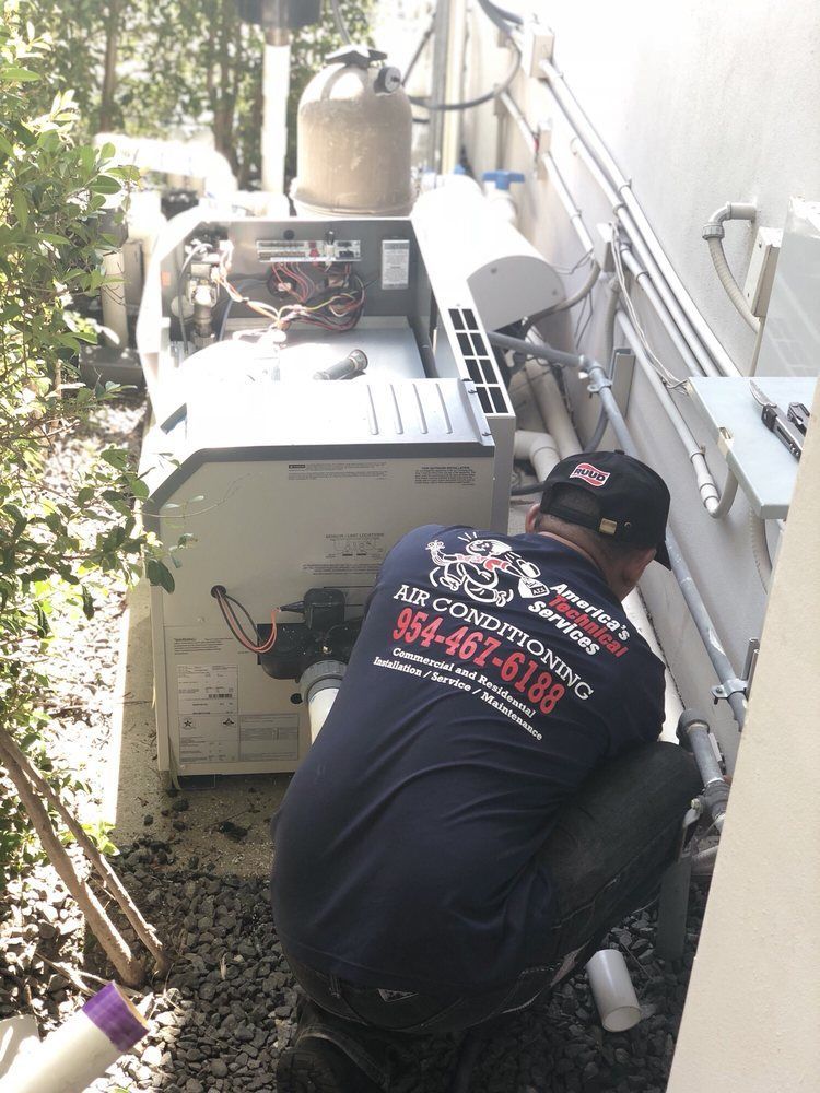 HVAC technician working on outdoor equipment; gray and white machinery next to a building.