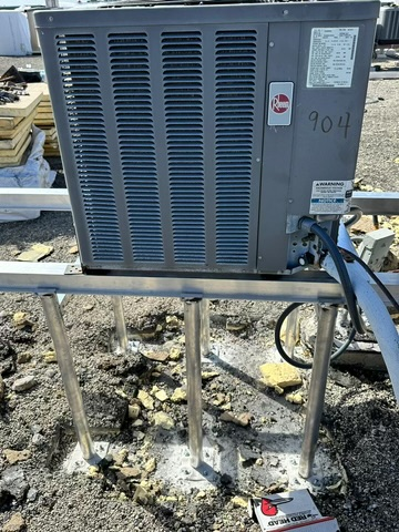 Air conditioning unit on a raised metal frame on a rooftop.
