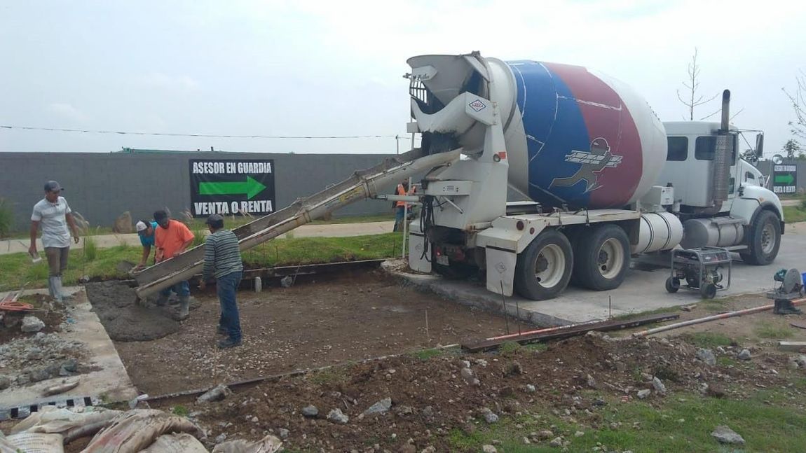 Un camión hormigonera está vertiendo hormigón en un agujero.