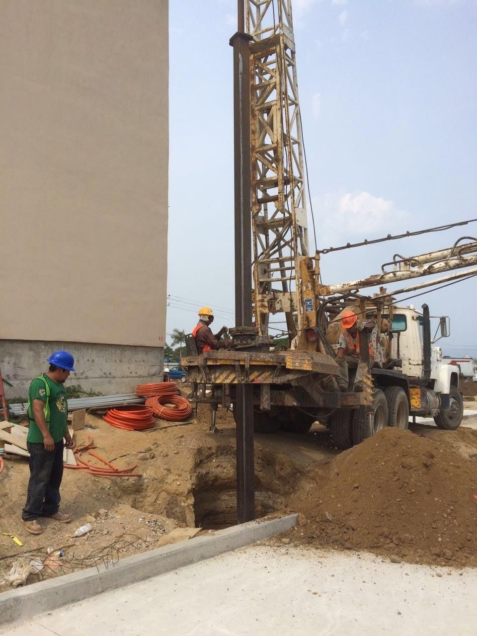 Un hombre con una camisa verde está parado frente a un sitio de construcción.