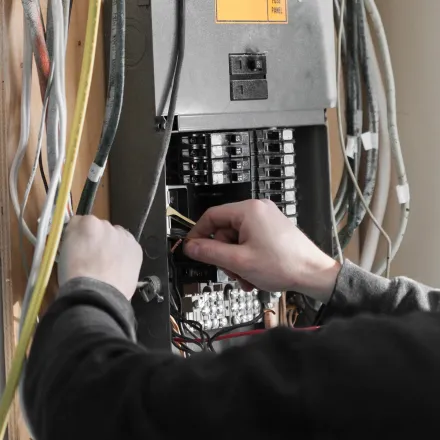 Grounded Electric - A man is working on an electrical panel with a sticker on it that says t4