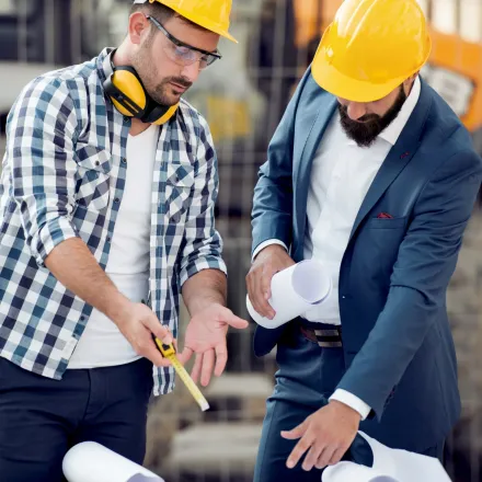 Grounded Electric - Two men wearing hard hats and safety glasses are working on a construction site.