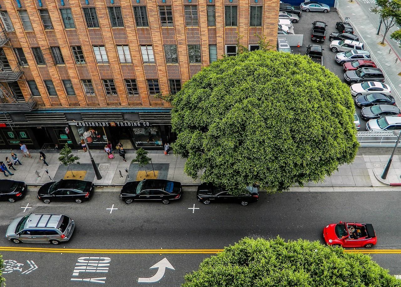 An aerial view of a street with a red car driving down it