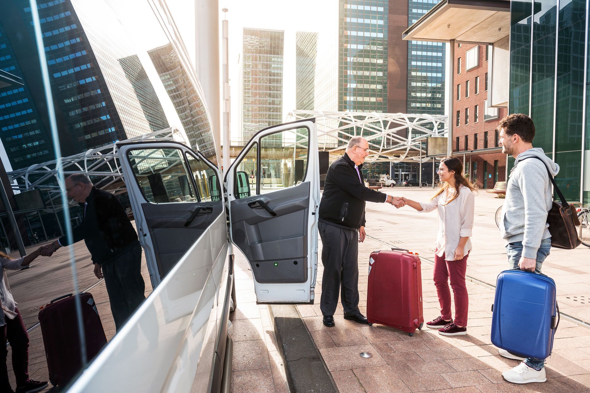A man is shaking hands with a woman in front of a van.