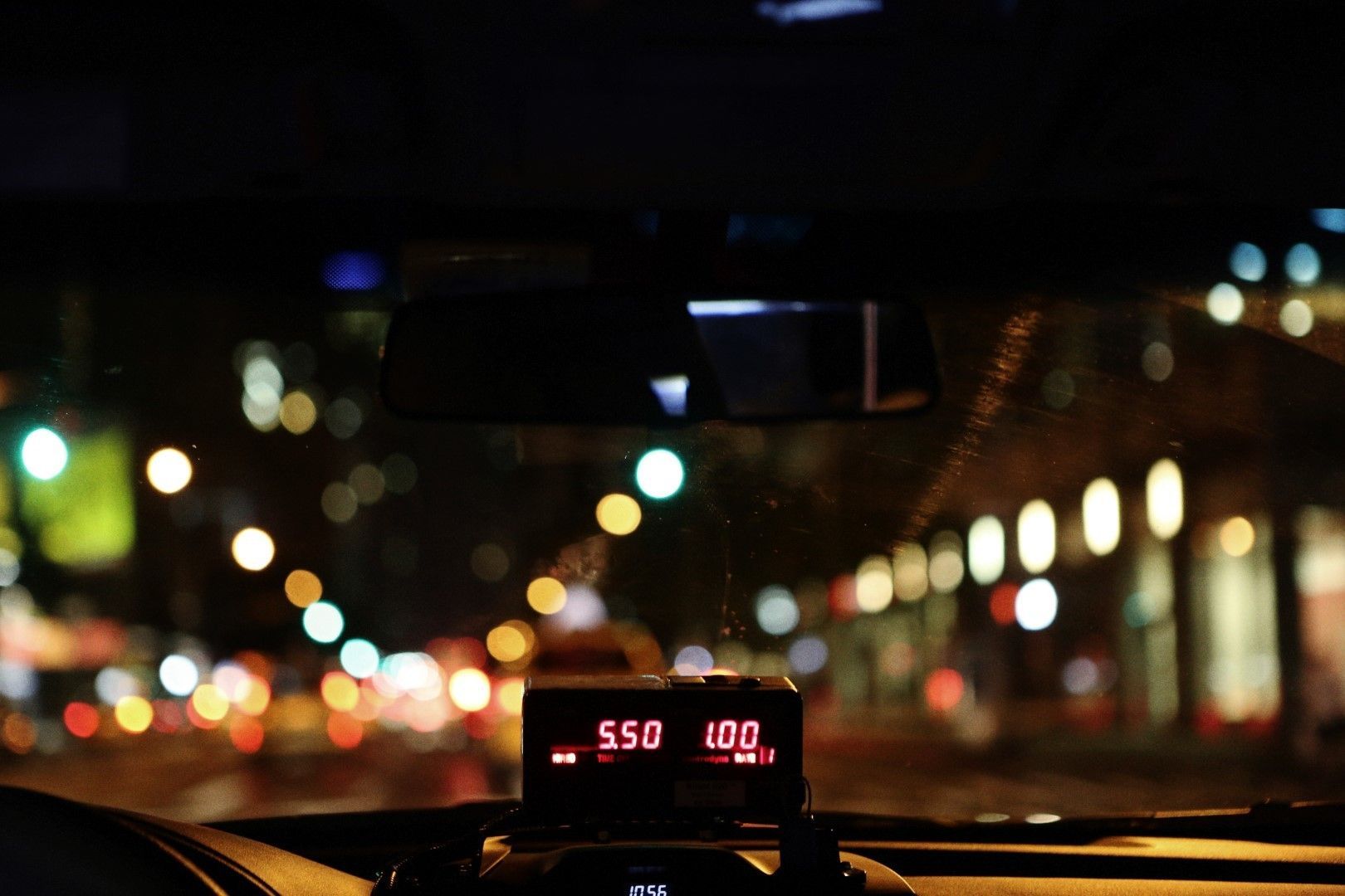 A taxi cab is driving down a city street at night.