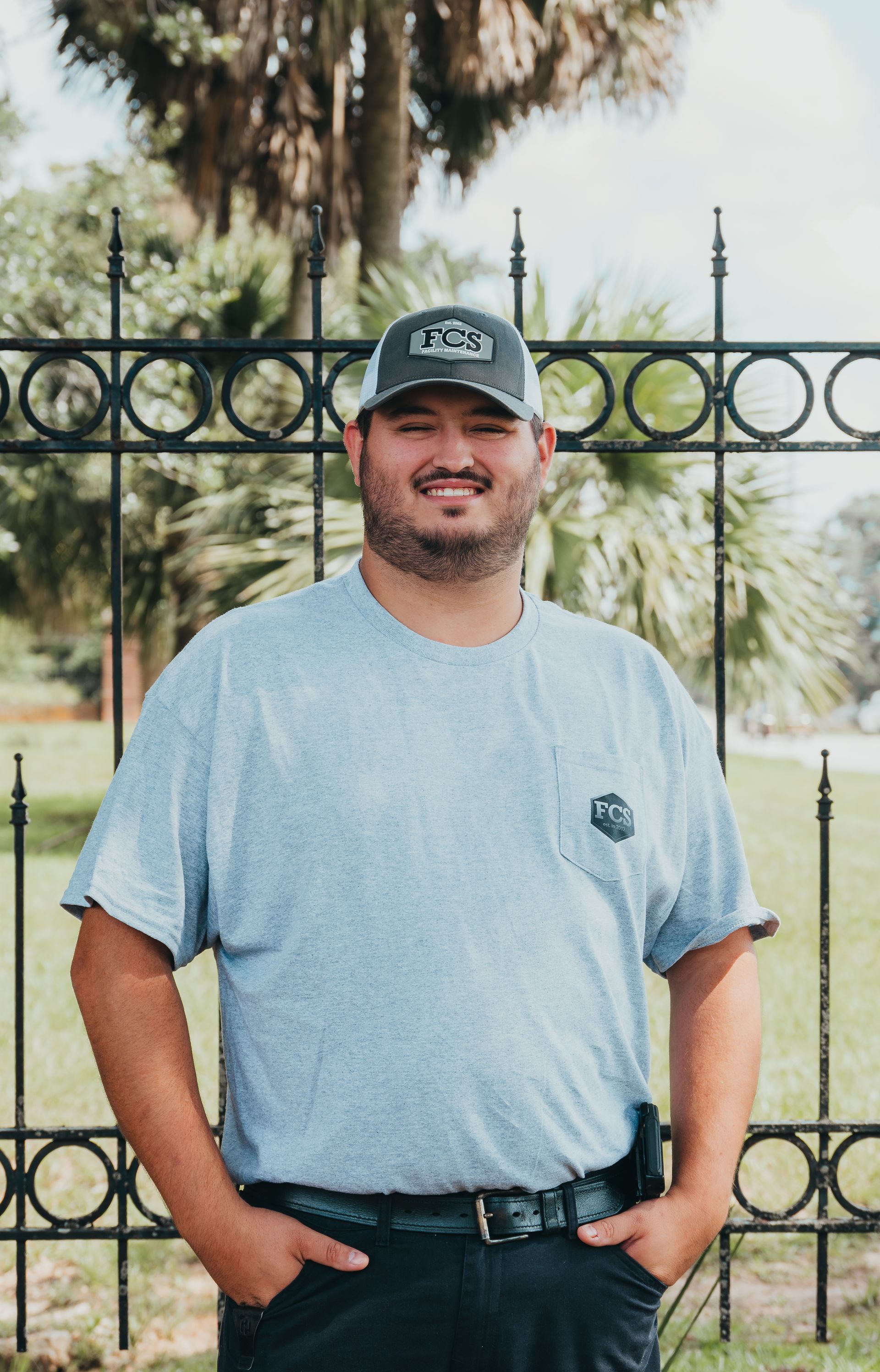 A man with a beard is wearing a hat and a gray shirt.