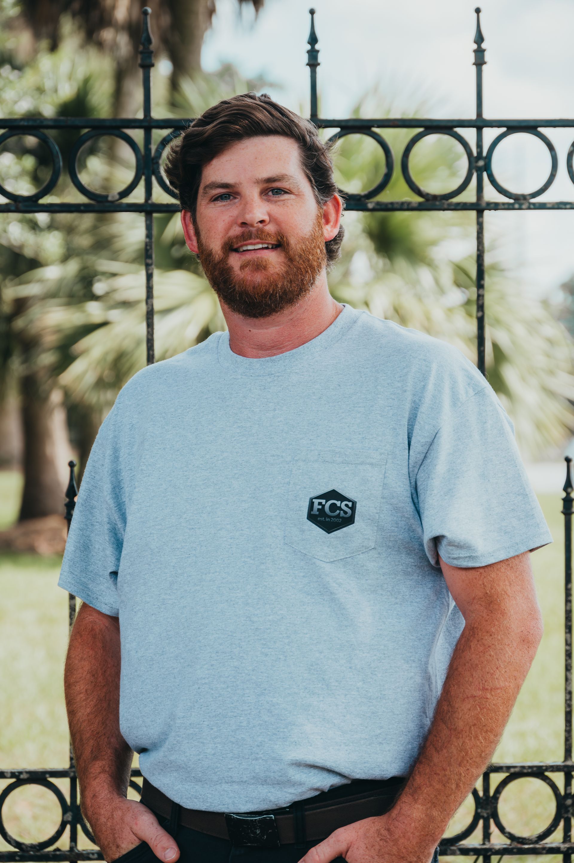 A man with a beard is wearing a hat and a gray shirt.