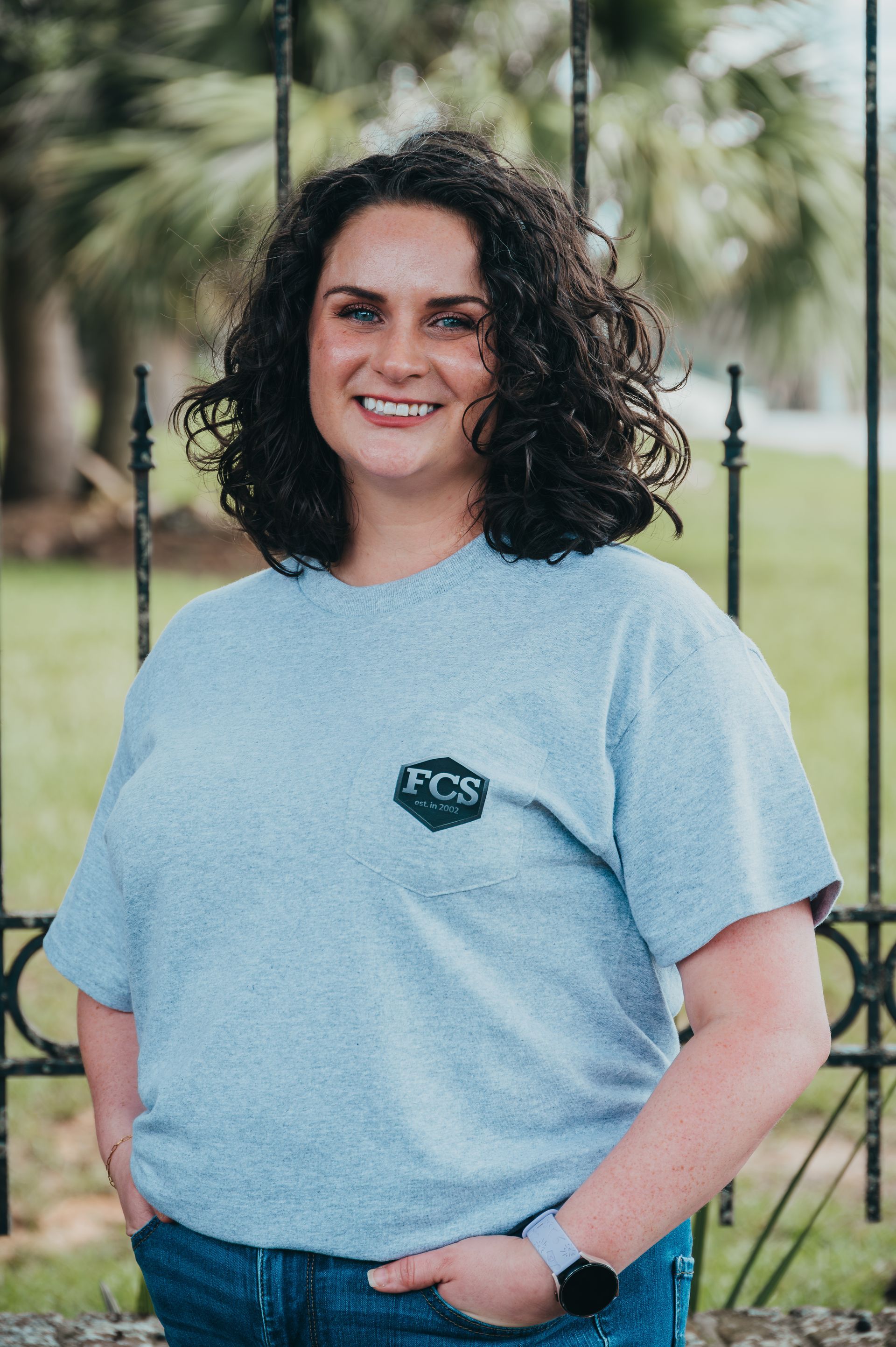 A woman is wearing a gray t-shirt and smiling.