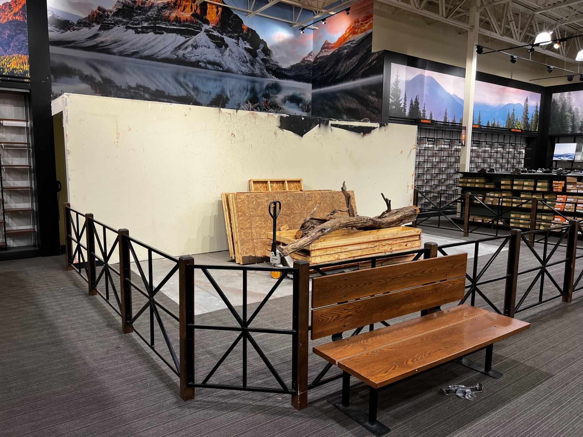 A wooden bench is sitting in front of a fence in a store.