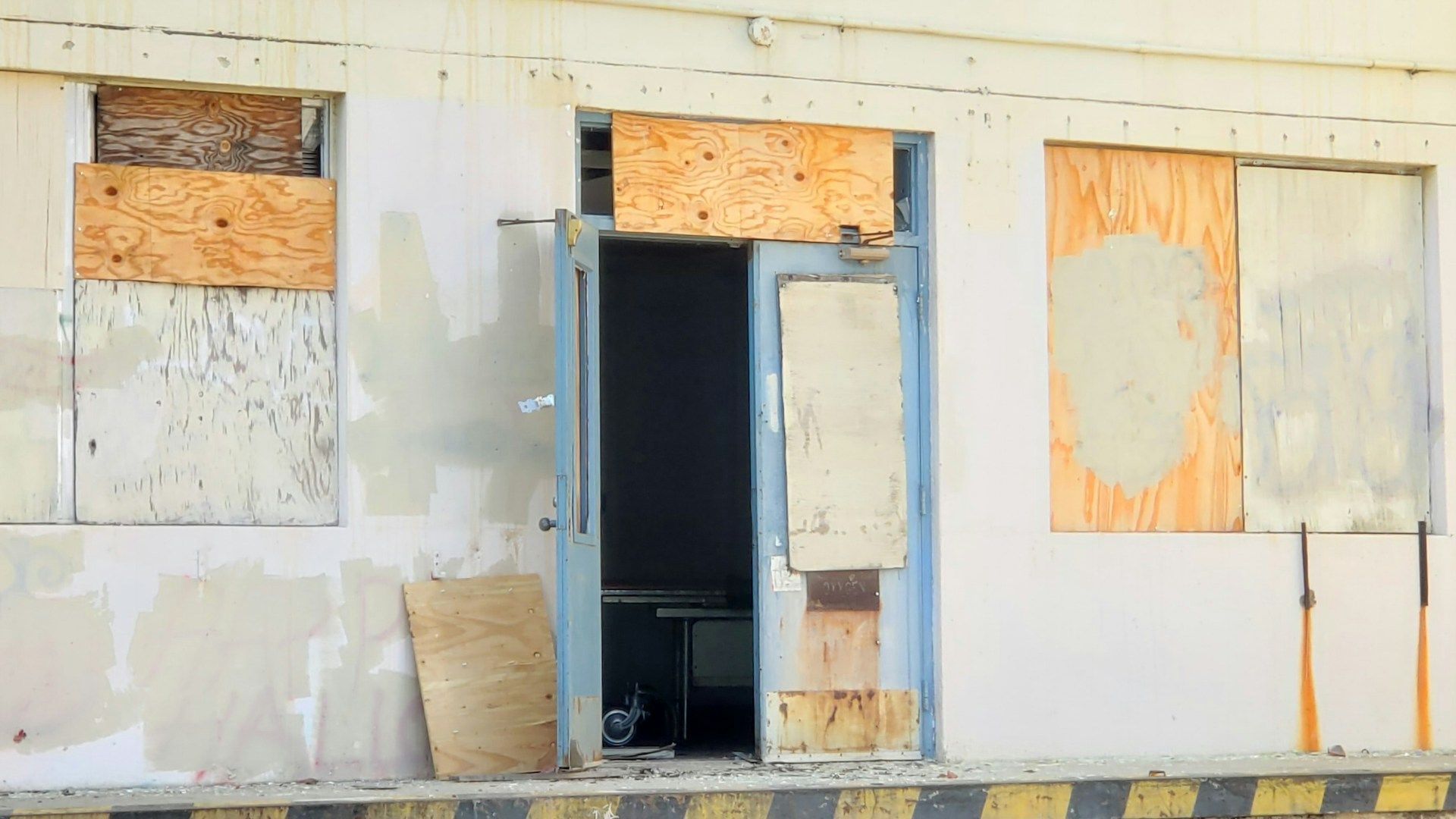 An old building with a door and windows boarded up.