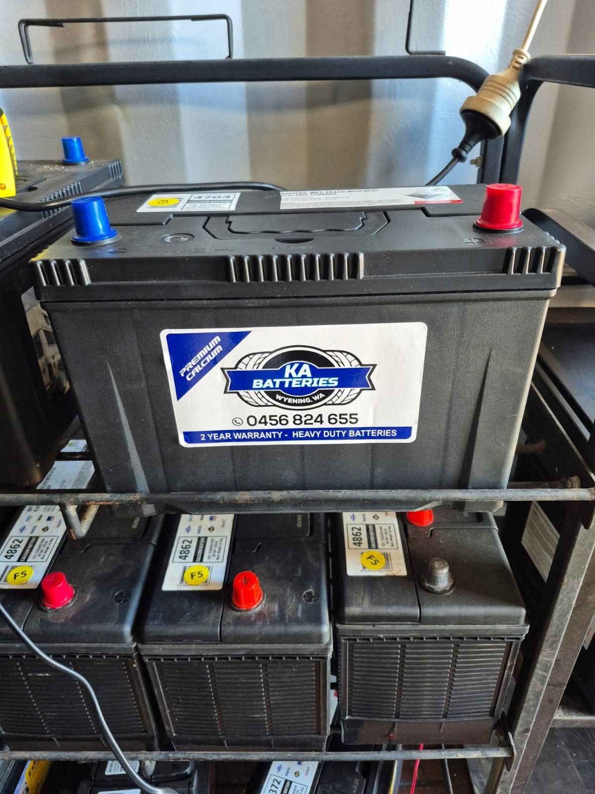 Battery display at a store, with stacked Bosch boxes and a blue sign reading “Batteries Sold Here.”