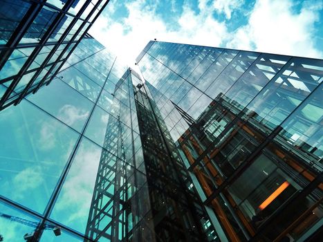 Looking up at a tall glass building with a blue sky in the background