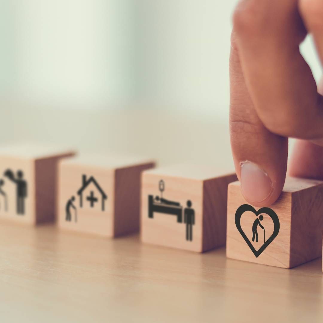 A person is holding a wooden block with a heart on it.