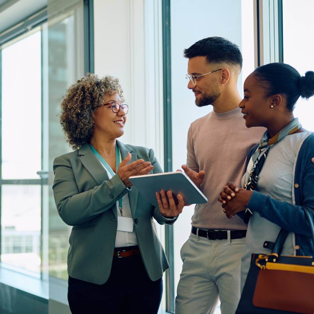 A woman is holding a tablet while talking to two men