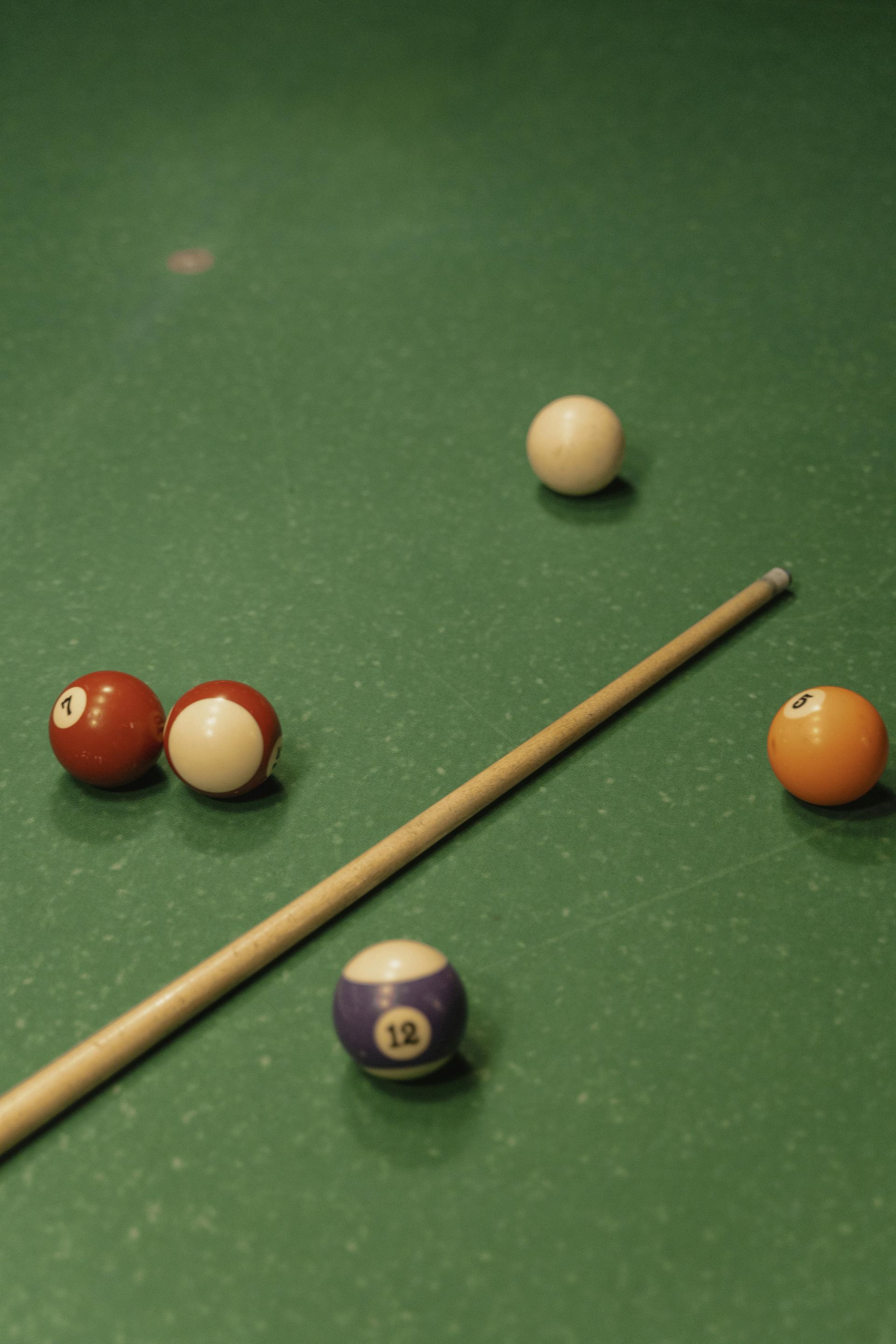 Pool table with a cue stick and several billiard balls.