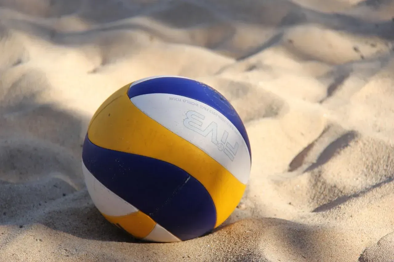 Volleyball on sand, featuring blue, yellow, and white panels.