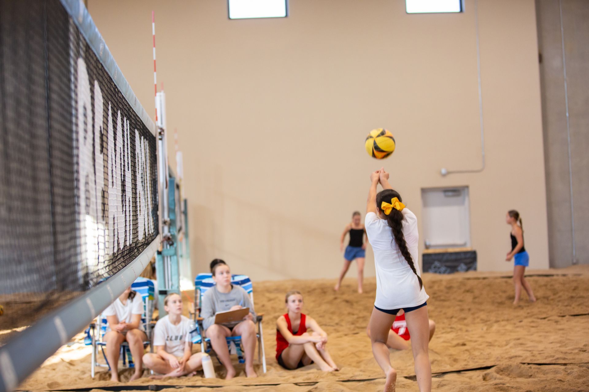 Beach volleyball game: players, net, sandy court, mountains in background, sunny day. Beach volleyball game: players, net, sandy court, mountains in background, sunny day.