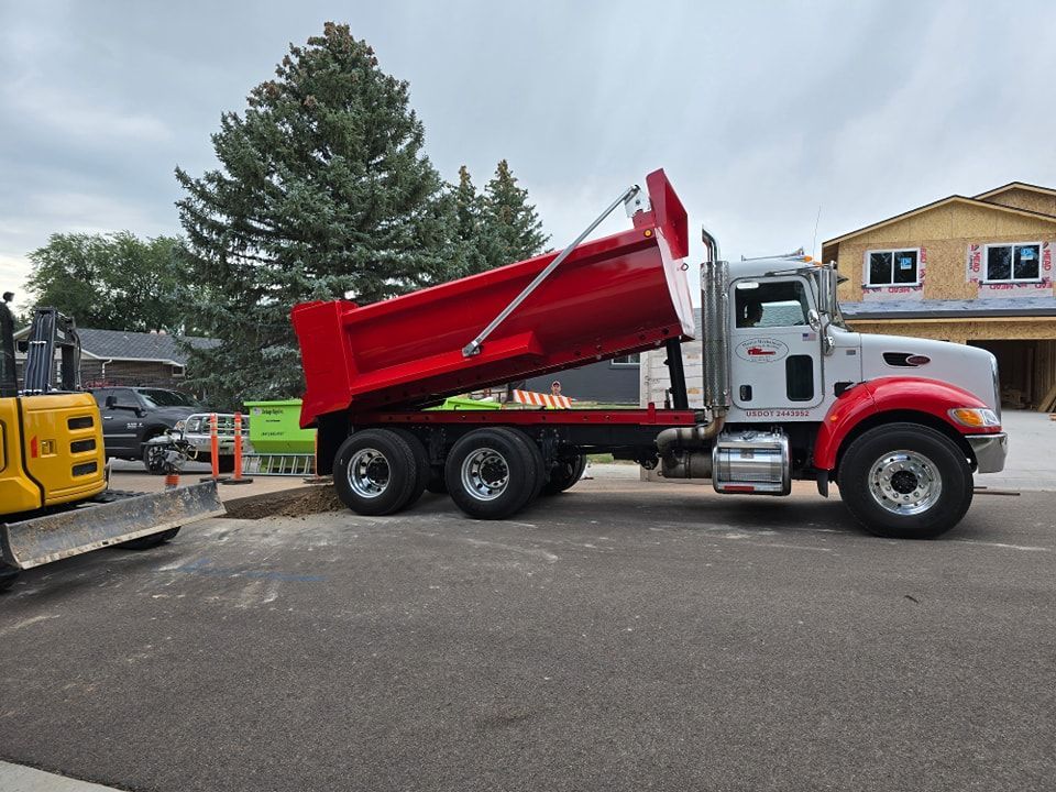 A dump truck is parked in front of a house under construction.
