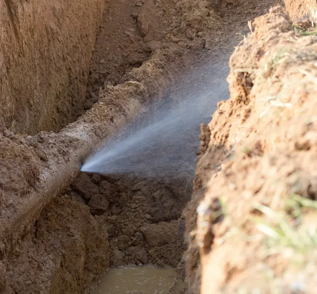 A hole in the ground with water spraying out of it.