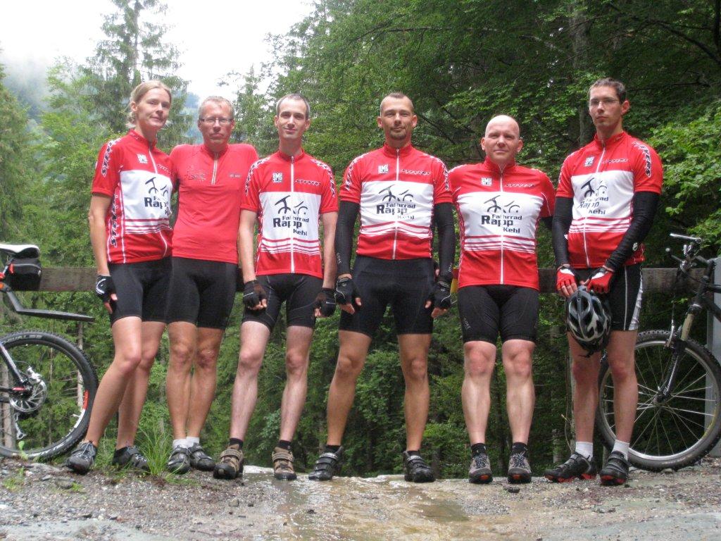 A group of cyclists are posing for a picture with their bikes