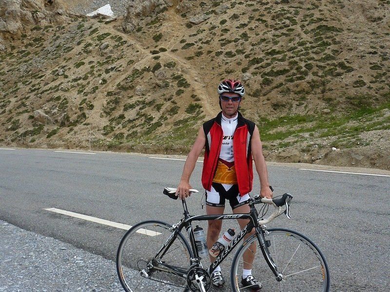 A man is standing next to a bicycle on the side of the road