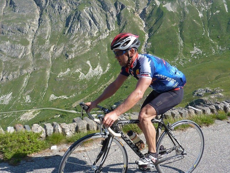 A man wearing a helmet is riding a bike down a road