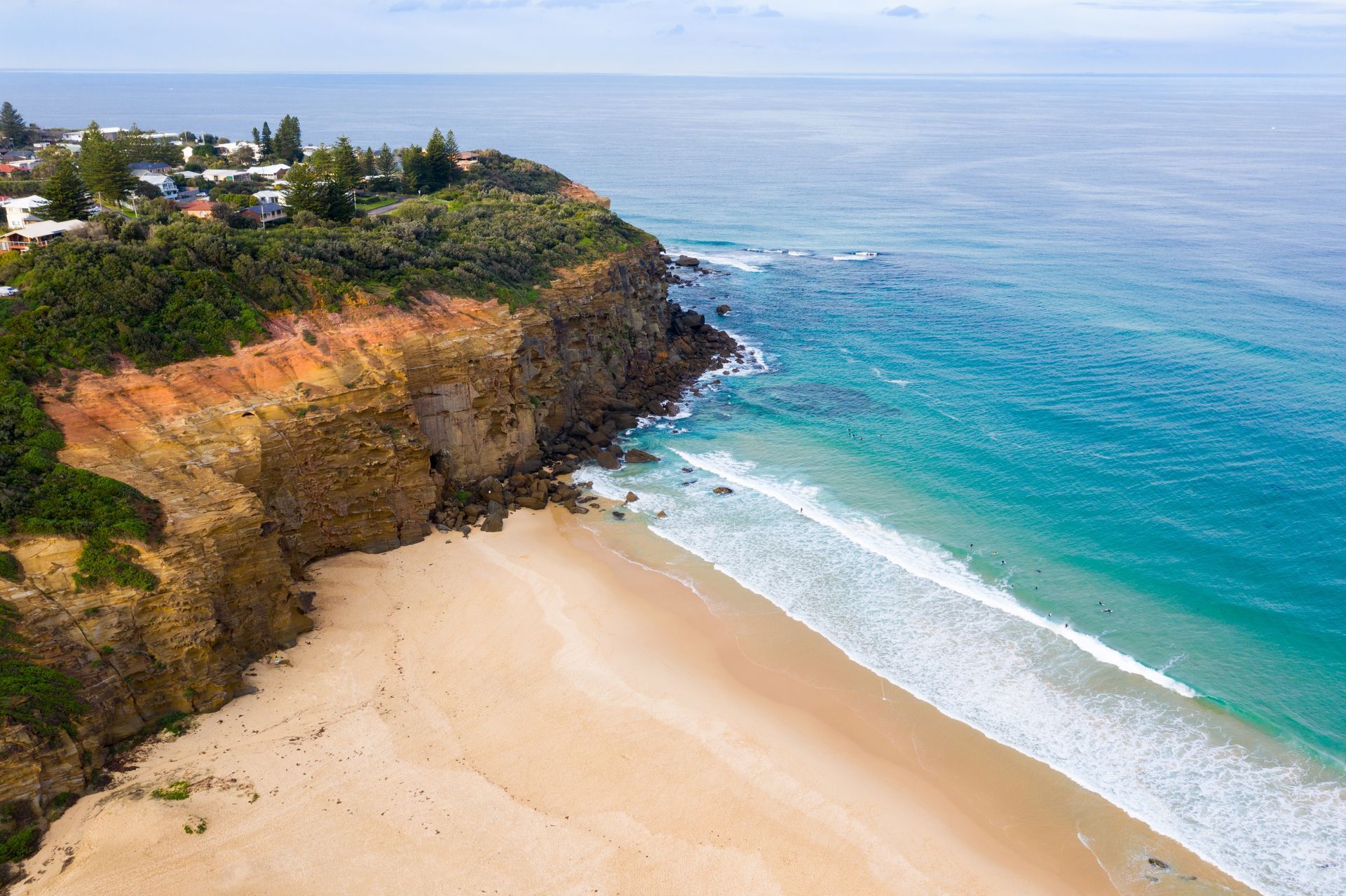 Sandy Beach Meets Turquoise Ocean Below a Rocky Cliff With Homes — Lake Macquarie Mobile Locksmiths in Redhead, NSW