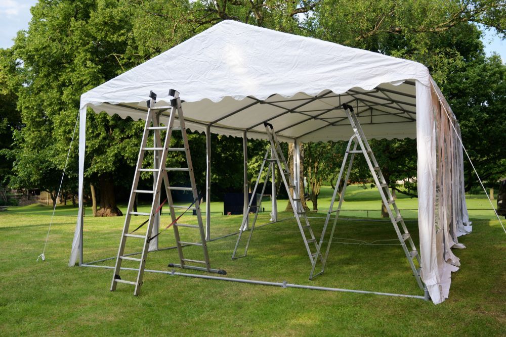 A White Tent Is Being Built In A Grassy Field With A Ladder — Johnny Farming Company In Ooralea, QLD
