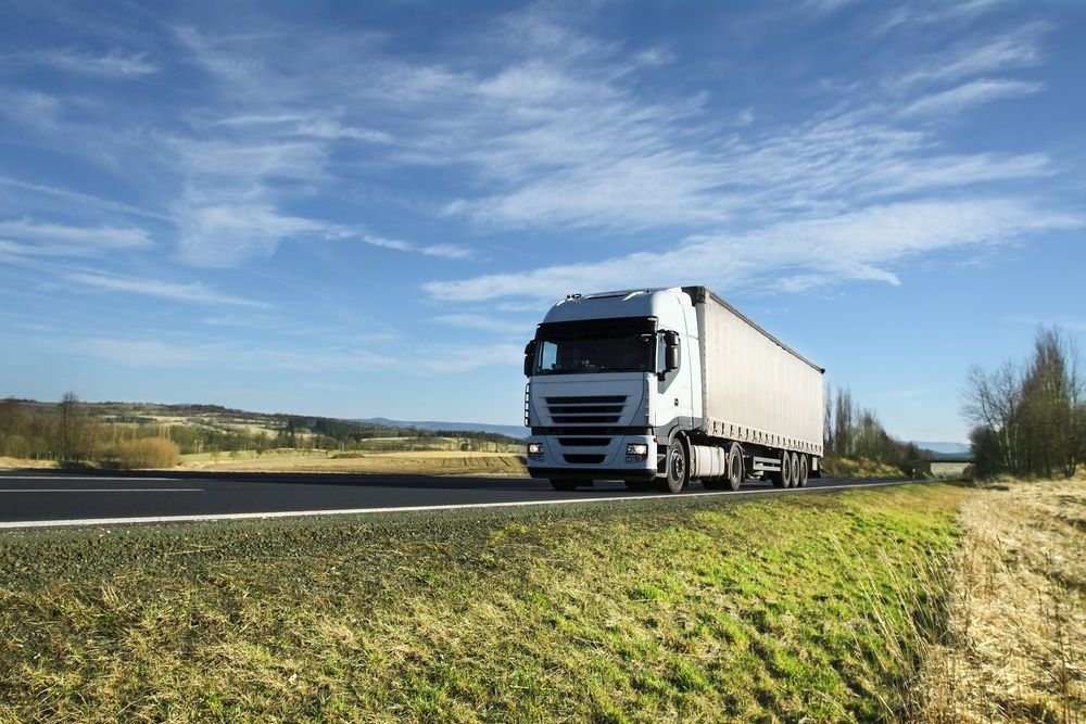 A White Semi Truck Is Driving Down A Country Road — Johnny Farming Company In Ooralea, QLD