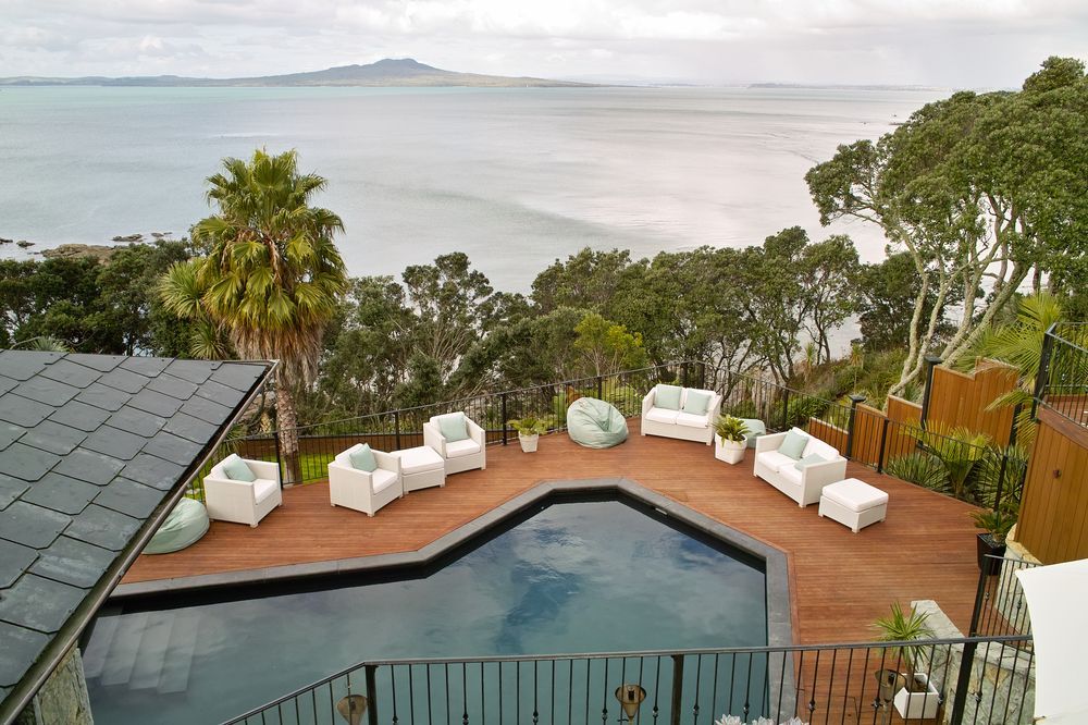 Poolside Lounge Area With Ocean View; White Furniture on Wooden Deck, Cloudy Sky — Gympie Fence Inspections in Cooroy, QLD