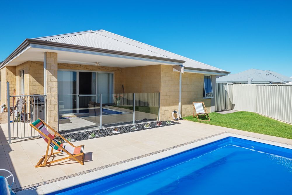 Backyard With a Swimming Pool, Patio, and Modern House With Glass Doors — Gympie Fence Inspections in Gympie, QLD