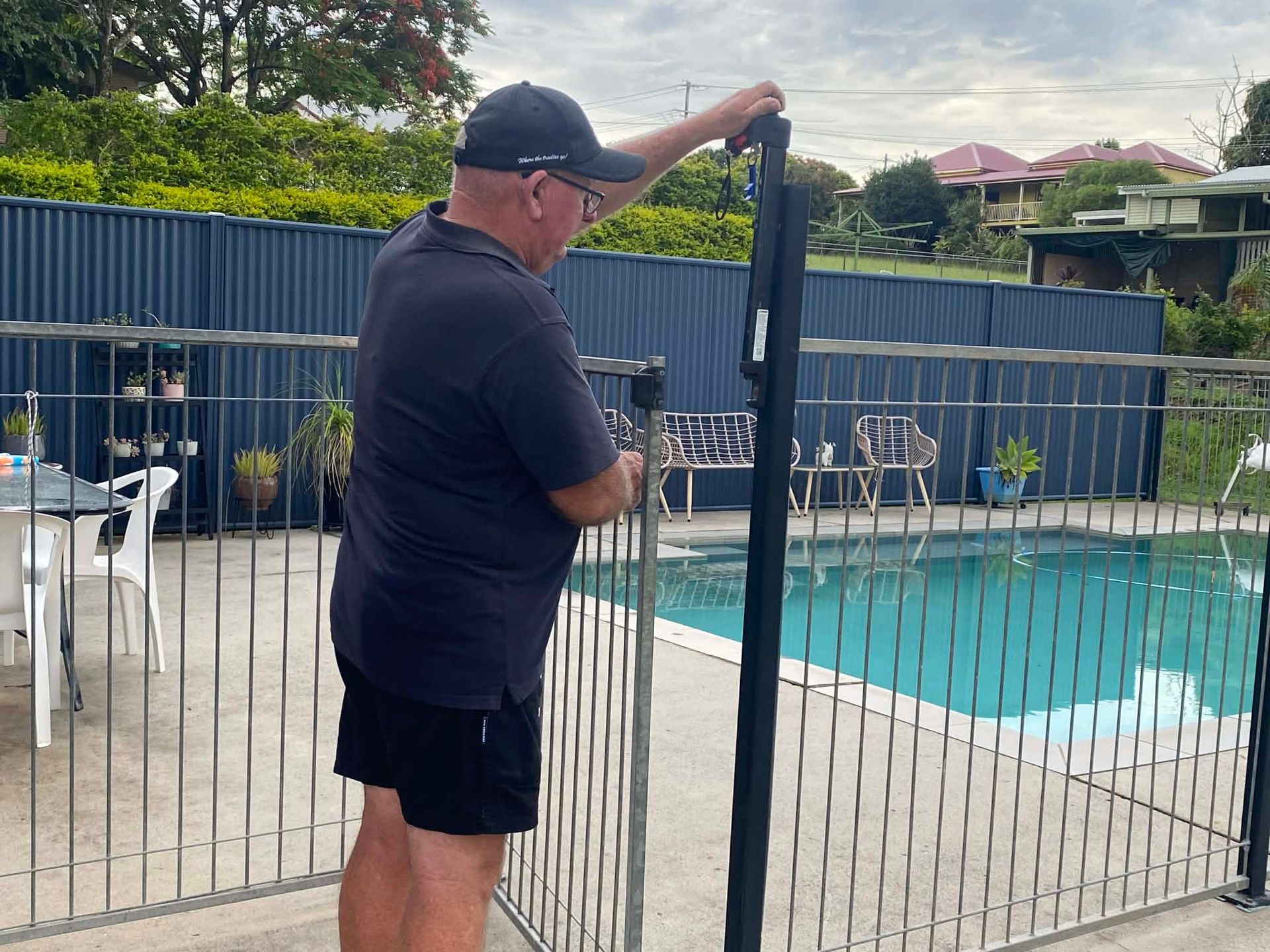 Man Adjusting a Black Roll-up Pool Fence — Gympie Fence Inspections in Gympie, QLD