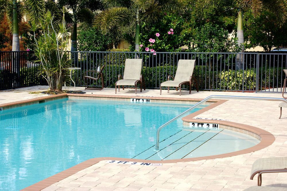 Poolside area with blue water pool, lounge chairs, and metal railing. — Gympie Fence Inspections in Tin Can Bay, QLD
