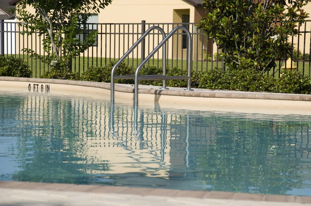 Pool with stainless steel ladder and black fence in the background. — Gympie Fence Inspections in Cooroy, QLD