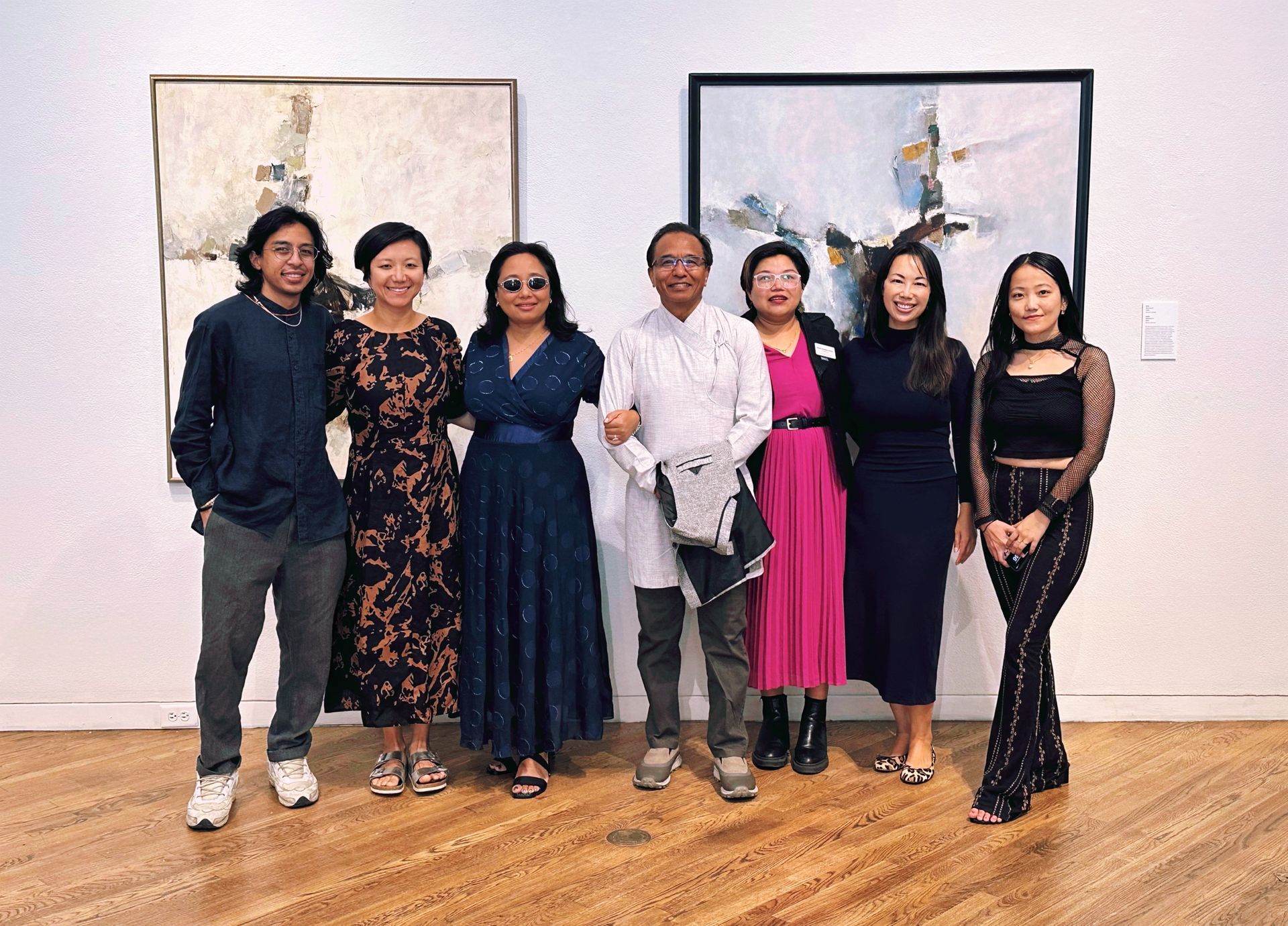 Group of people posing by abstract art in a gallery setting.