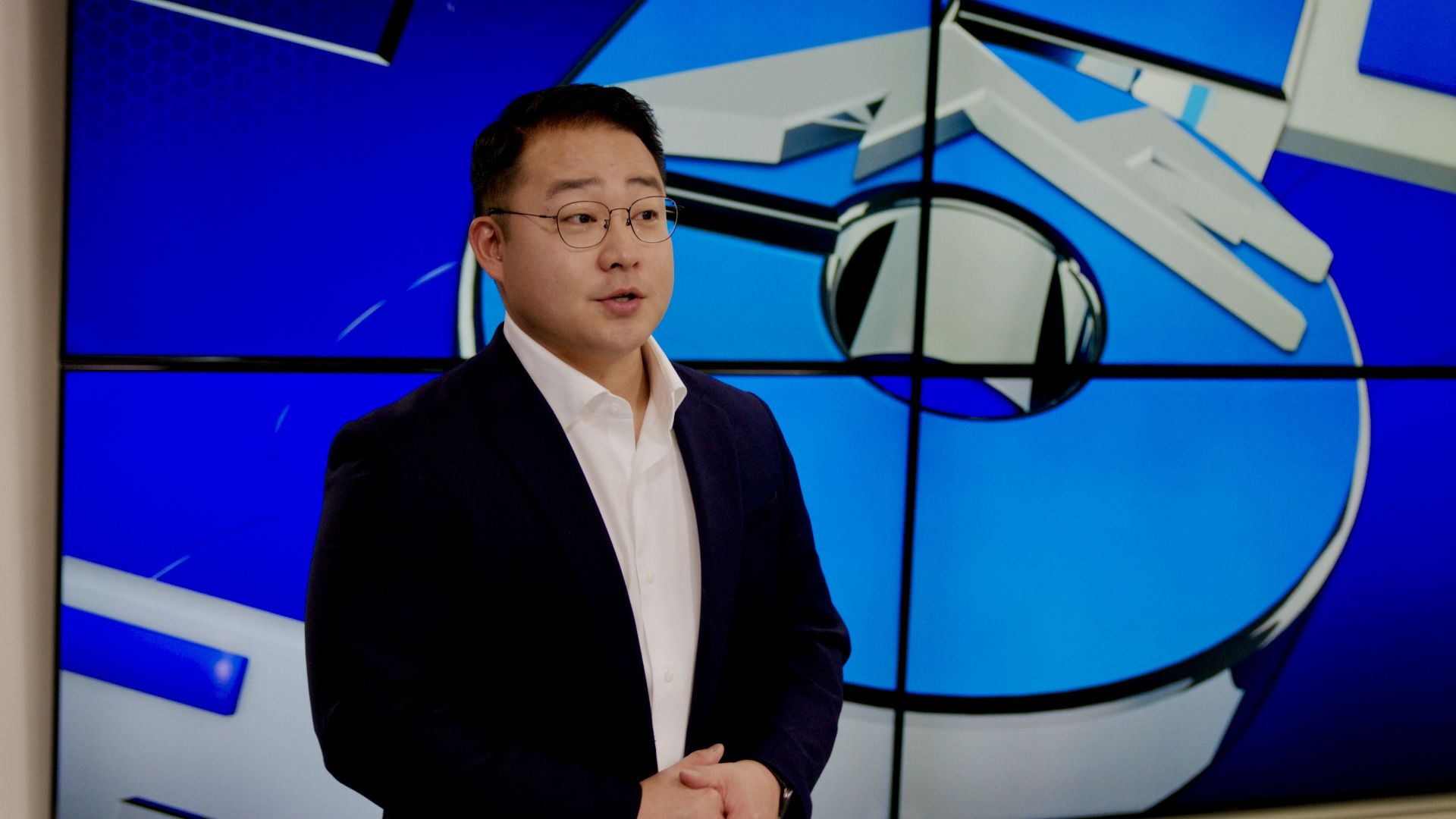 Peter Choi stands in front of a blue-screened background.