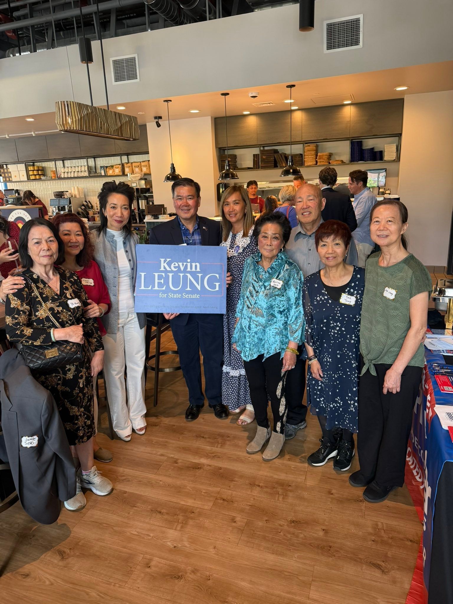 Group of people posing in a café, holding a blue “LUNG” sign.