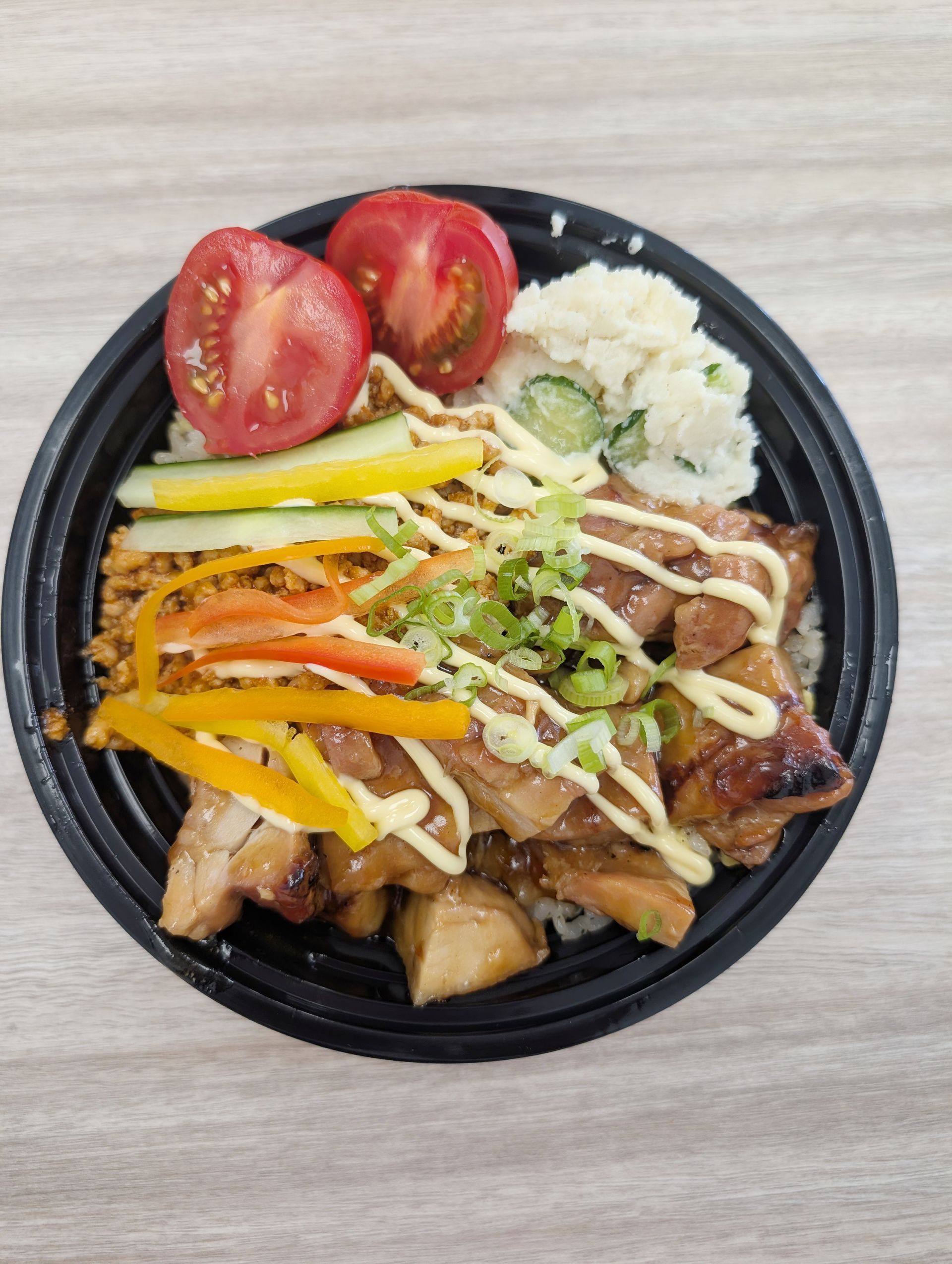 Teriyaki chicken bowl with rice, tomatoes, cucumber, and potato salad.