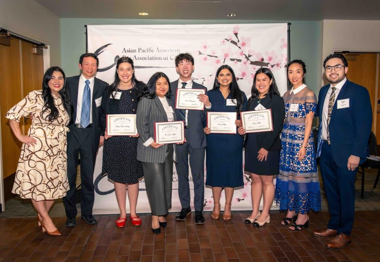 Group of people holding certificates at an awards ceremony in a banquet hall