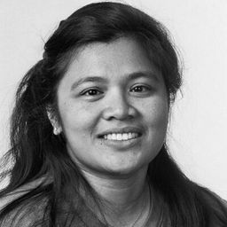 Woman with dark hair, smiling, wearing a pearl earring, in a black and white portrait.