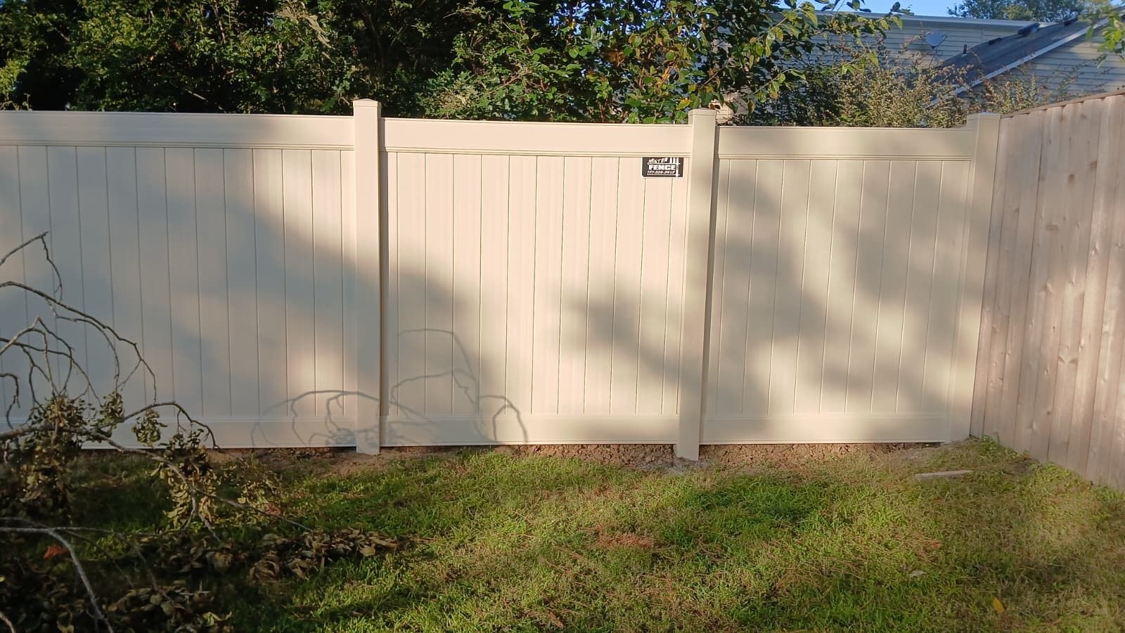 White vinyl fence with a gate in a grassy yard.