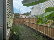 Wooden fence in a narrow yard between two houses; overcast sky.